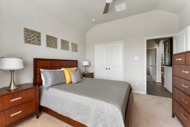 a bedroom with a bed and a lamp on dresser