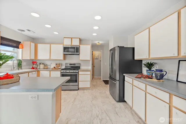 a kitchen with stainless steel appliances granite countertop a refrigerator sink stove microwave and cabinets