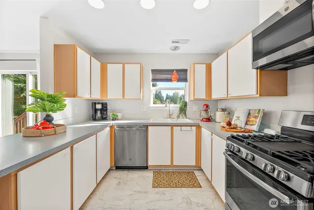 a kitchen with stainless steel appliances a stove a sink cabinets and a window