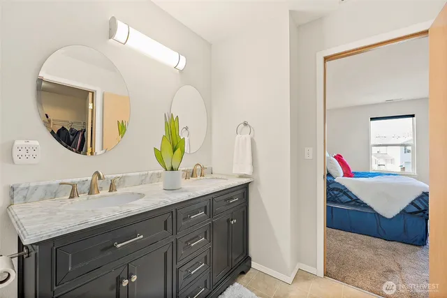 a en suite bathroom with a granite countertop double vanity sink and a mirror