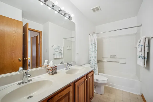 a bathroom with a sink toilet double vanity and shower