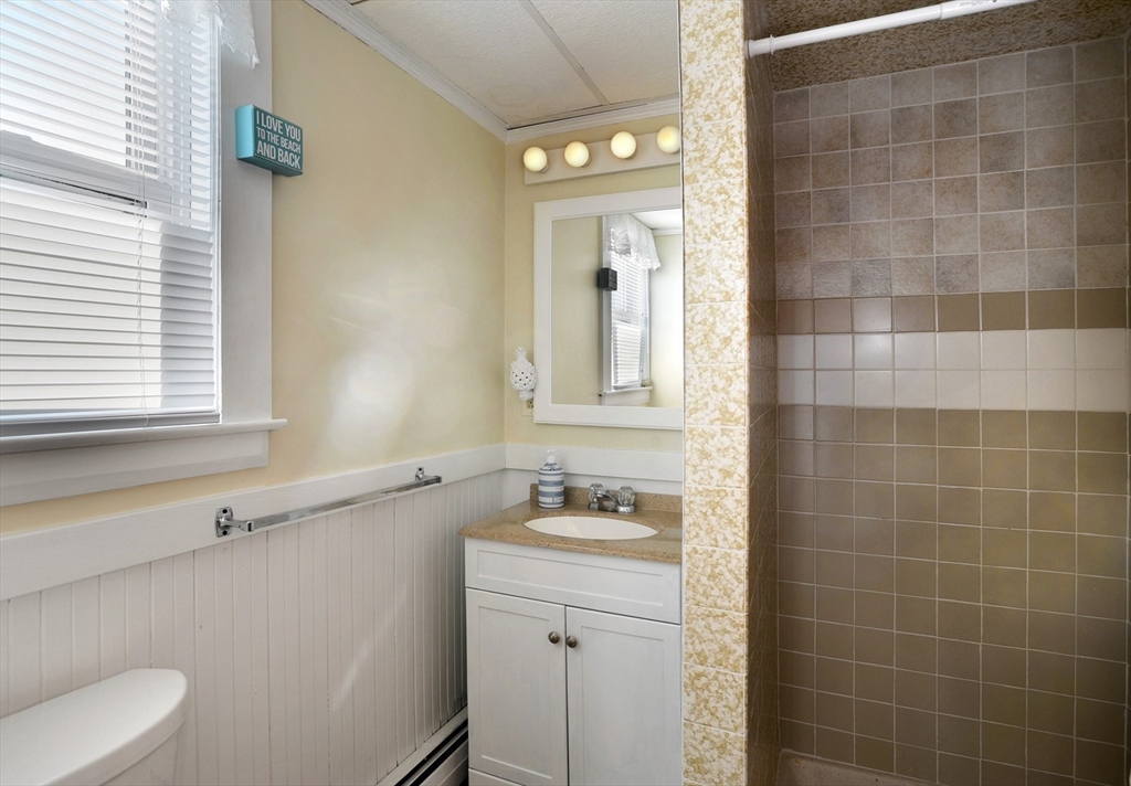 69 Beach Avenue Hull, MA 02045 - Photo 8 of 27 a bathroom with a granite countertop sink a toilet a mirror and a window