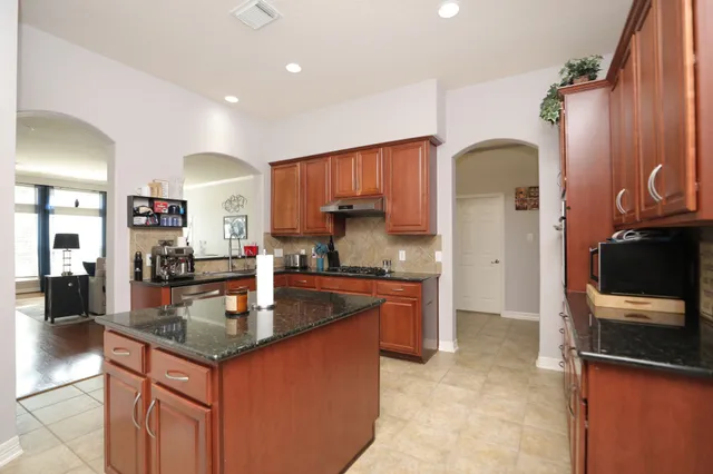 a kitchen with granite countertop a sink stove and refrigerator