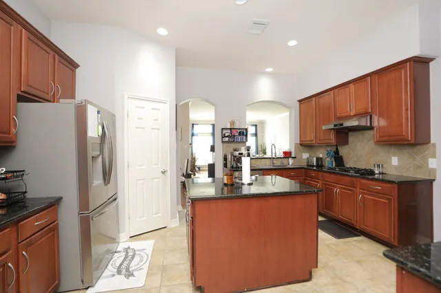 a kitchen with stainless steel appliances granite countertop a refrigerator a sink dishwasher a stove top oven a refrigerator and cabinets with wooden floor