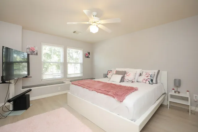 a bedroom with a large bed and a flat tv screen on dresser