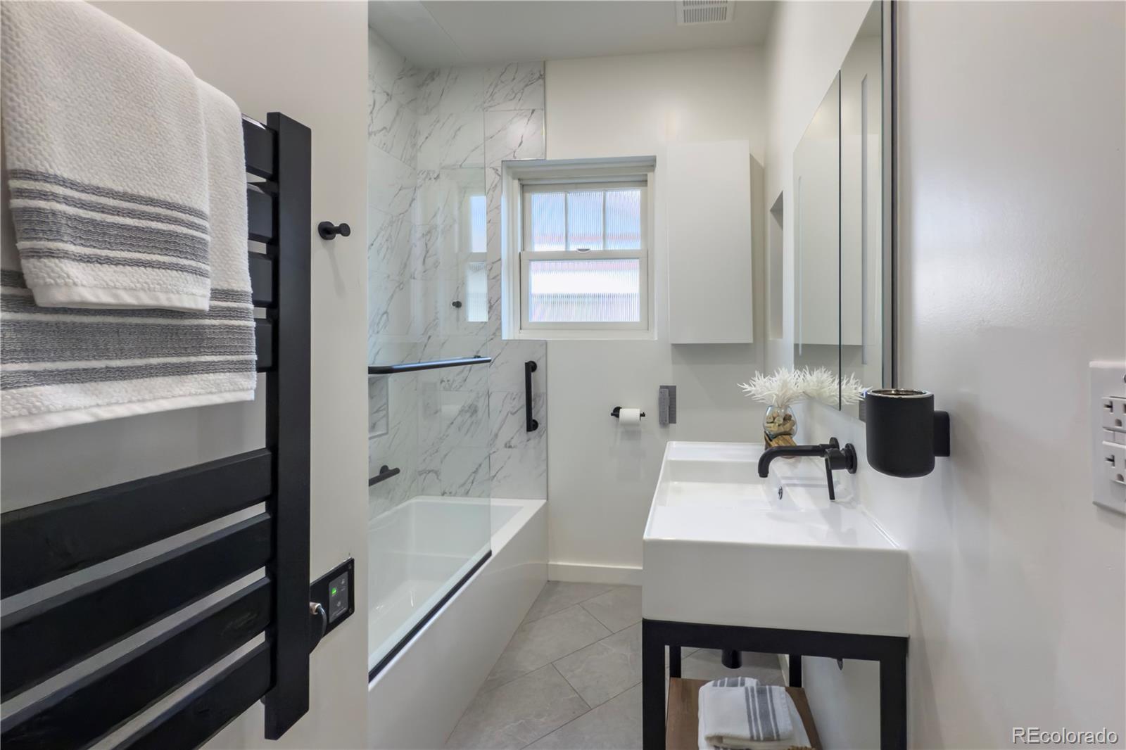926 Steele Street Denver, CO 80206 - Photo 22 of 41 a bathroom with a sink a bathtub and a mirror