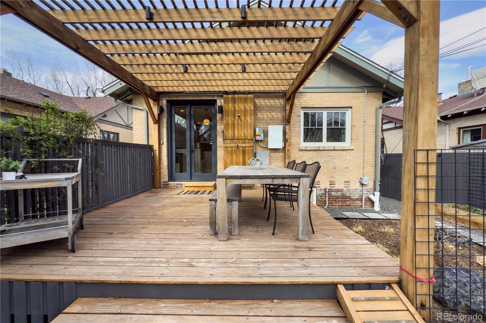 926 Steele Street Denver, CO 80206 - Photo 37 of 41 a view of a patio with table and chairs with wooden floor and fence
