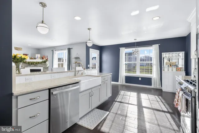 a large kitchen with granite countertop a large counter top space a sink stainless steel appliances and cabinets