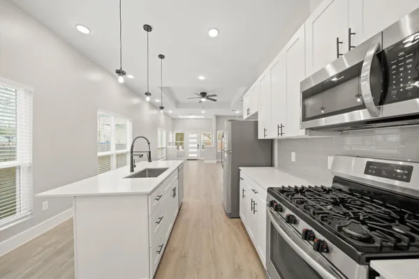 a kitchen with stainless steel appliances a sink a stove a refrigerator cabinets and a window