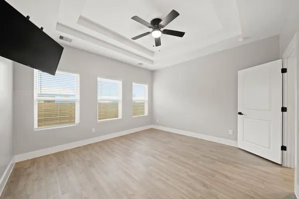 a view of an empty room with a window and wooden floor
