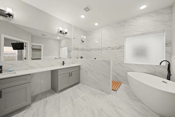 a spacious bathroom with a double vanity sink a mirror and a bathtub