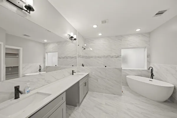 a spacious bathroom with a double vanity sink mirror and bathtub