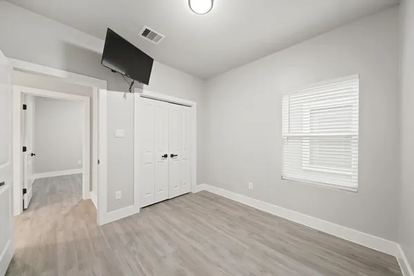 a view of an empty room with wooden floor and a window