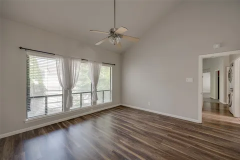 an empty room with wooden floor fan and windows