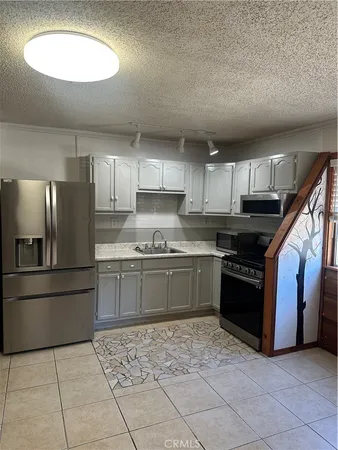 a kitchen with granite countertop a refrigerator and a stove top oven