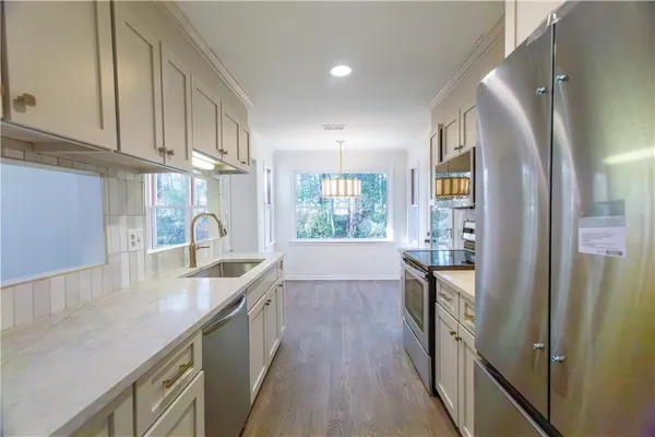 a kitchen with granite countertop a sink a counter space and stainless steel appliances