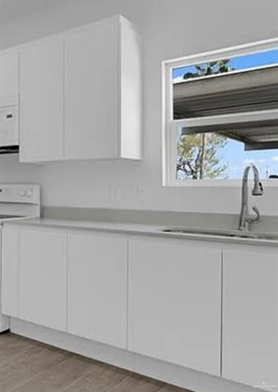 1403 Marcela Drive, Unit 3 Weslaco, TX 78599 - Photo 6 of 13 Kitchen view of white cabinetry, light countertops, light wood finished floors, and white appliances