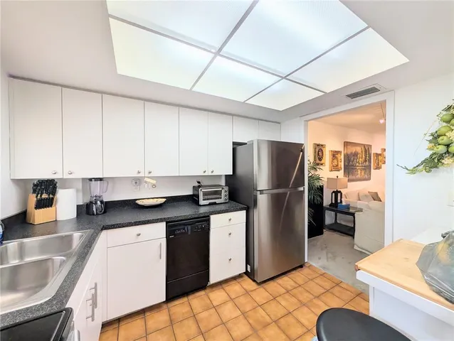 a kitchen with stainless steel appliances granite countertop a sink a stove a refrigerator a washer dryer and white cabinets