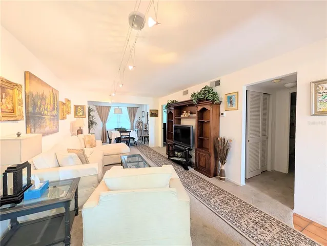 a living room with furniture a flat screen tv and a refrigerator