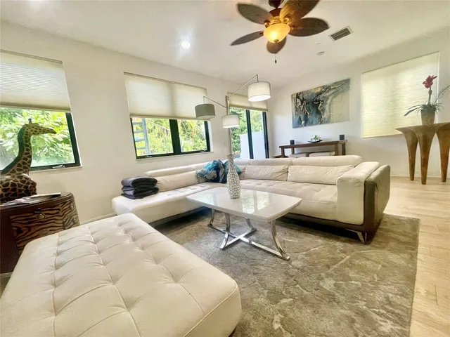 a living room with furniture a ceiling fan and a kitchen view
