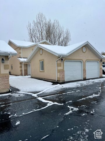 1518 Talon Drive Logan, UT 84321 - Photo 1 of 1 View of snowy exterior with driveway, brick siding, an attached garage, and stucco siding
