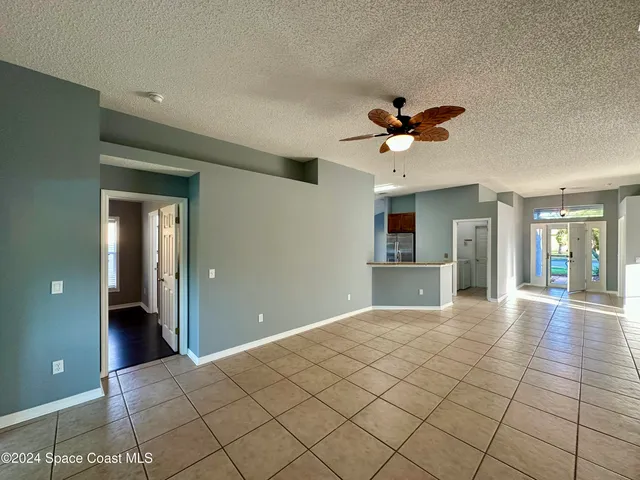 a view of a livingroom with a chandelier fan and windows
