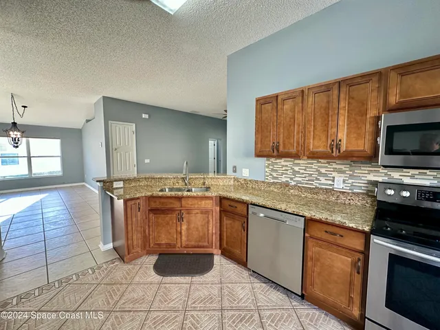 a kitchen with stainless steel appliances granite countertop a stove a sink and a microwave