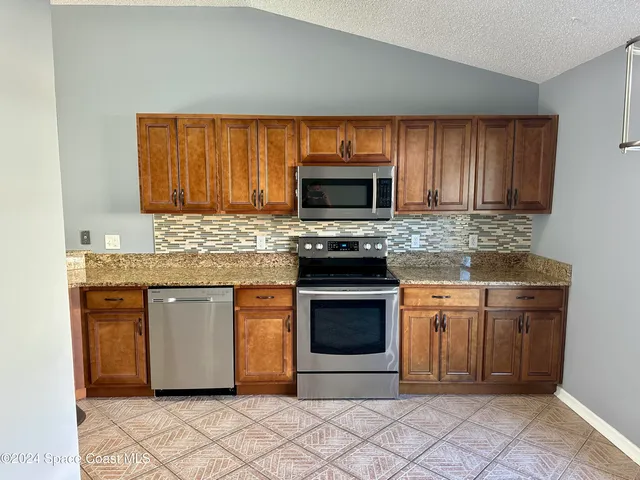 a kitchen with granite countertop a stove top oven microwave and cabinets