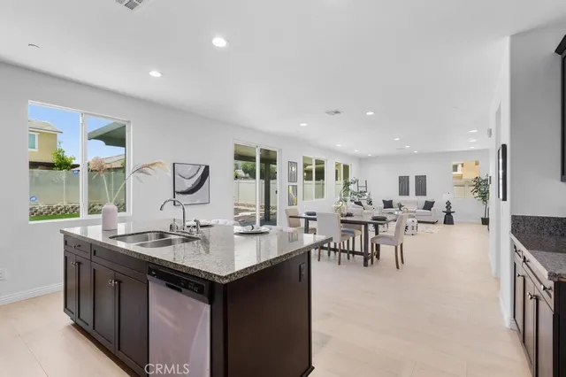 a dining hall with stainless steel appliances granite countertop a table chairs and a sink