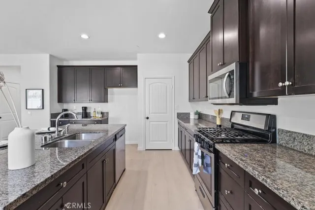 a kitchen with granite countertop stainless steel appliances a sink stove top oven and cabinets