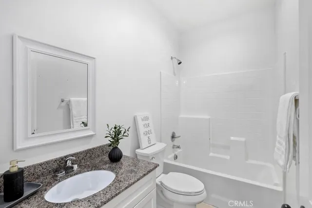 a bathroom with a granite countertop sink toilet a mirror and shower