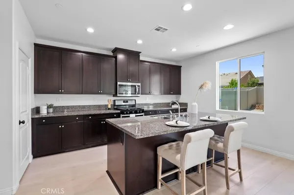 a kitchen with kitchen island granite countertop a sink counter top space appliances and cabinets
