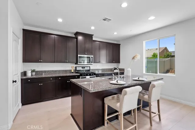 a kitchen with kitchen island granite countertop a sink counter top space appliances and cabinets