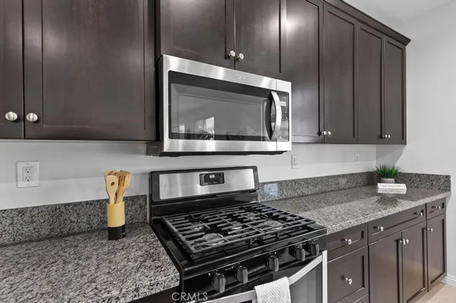 a kitchen with granite countertop a sink stove and cabinets