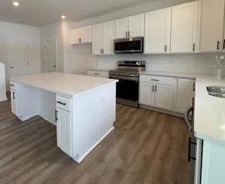 a kitchen with stainless steel appliances a stove top oven a sink a stove and white cabinets