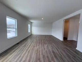 a view of empty room with window and wooden floor