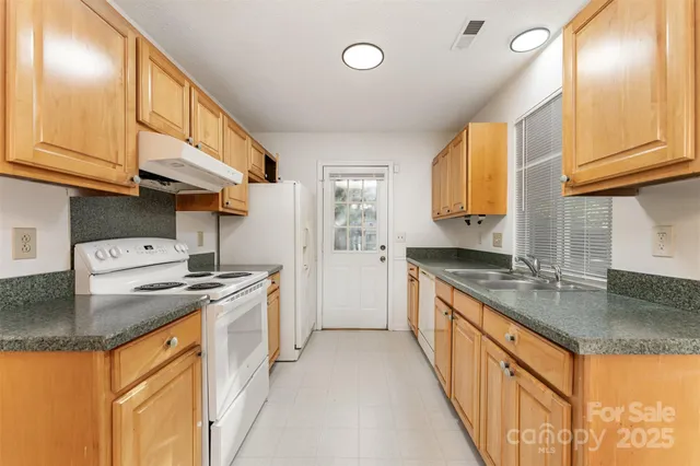 a kitchen with granite countertop a sink stove and refrigerator