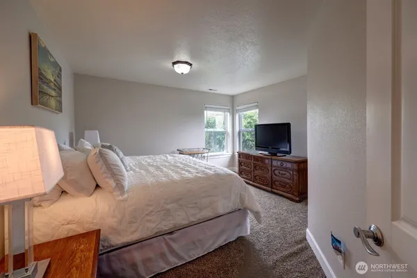 a bedroom with a bed a couch and a flat screen tv
