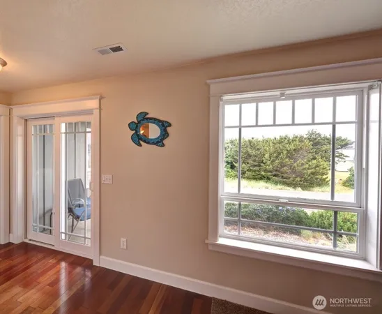 a view of an empty room with wooden floor and a window