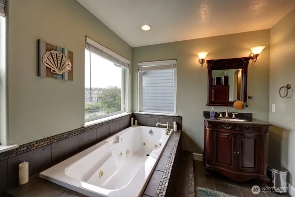 a bathroom with a bathtub a mirror a sink and a window