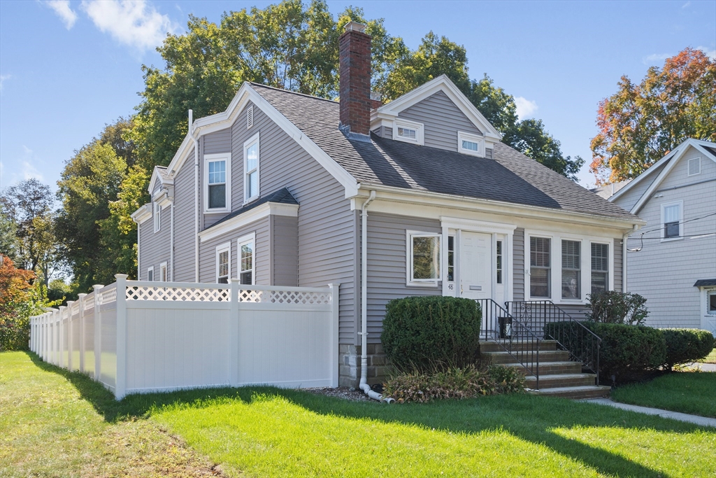 a front view of house with yard and trees in the background
