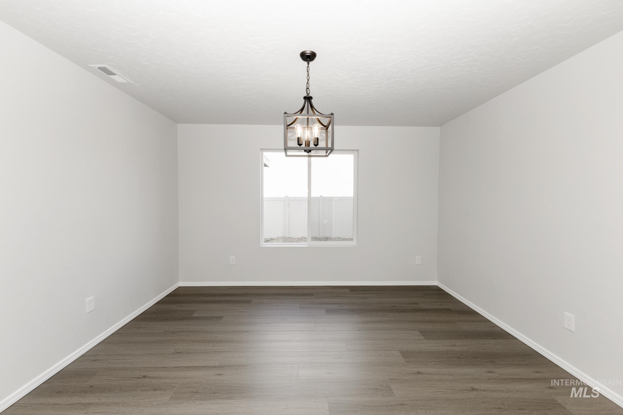 3070 South Maple Rnch Way Nampa, ID 83686 - Photo 15 of 33 Unfurnished room with wood finished floors and a chandelier