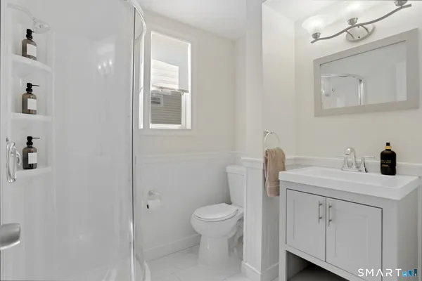 a bathroom with a toilet a sink a mirror and a window