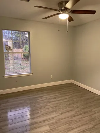 a view of an empty room with wooden floor and a window