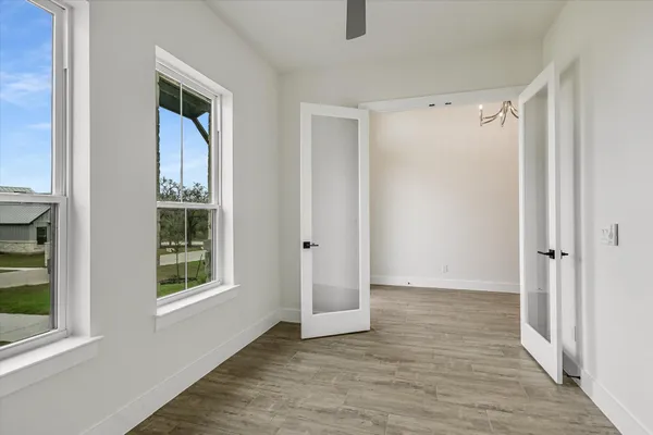 a view of an empty room with wooden floor and a window