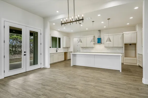 a large white kitchen with kitchen island a large island a stove a refrigerator cabinets and living room view