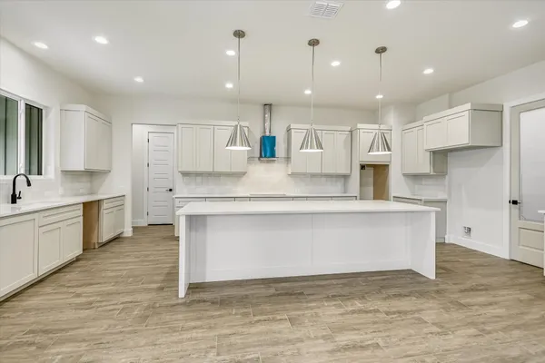 a large white kitchen with kitchen island a sink stainless steel appliances and cabinets