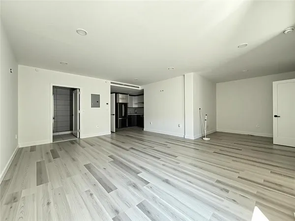 a view of an empty room with wooden floor and closet
