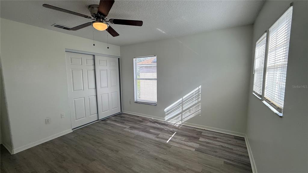 4484 Philadelphia Circle Kissimmee, FL 34746 - Photo 25 of 56 an empty room with wooden floor fan and windows