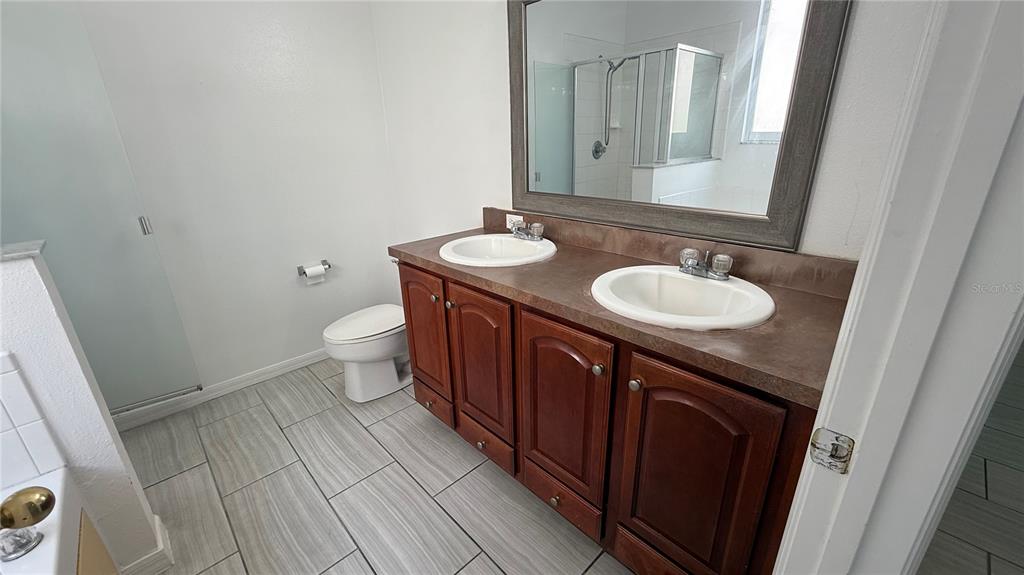 4484 Philadelphia Circle Kissimmee, FL 34746 - Photo 45 of 56 a bathroom with a granite countertop toilet sink and mirror